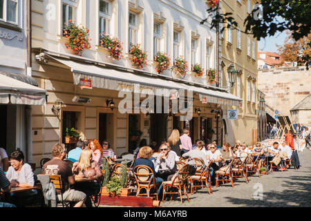 Prague, September 29, 2017: A popular street cafe near the Charles Bridge. Local residents and tourists rest, eat and communicate on a sunny warm day. Stock Photo