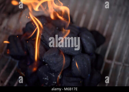macro closeup of charcoals on grill with flames rising up Stock Photo