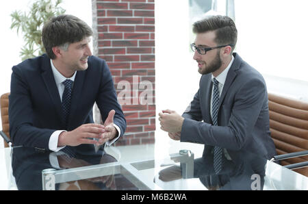 Two businessmen discussing tasks sitting at office table. Stock Photo