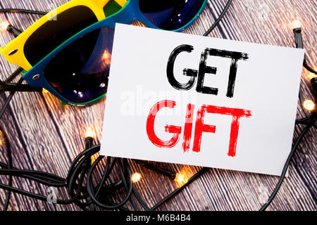 Writing text showing Get Gift. Business concept for Free Shoping Coupon written on old wood wooden background with sunglasses Stock Photo