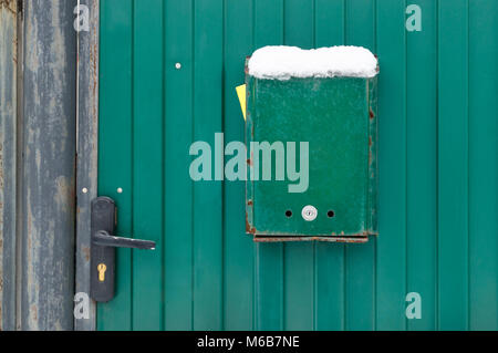 The mailbox is green on the metal gate of the house with a lock and a handle. Green background Stock Photo