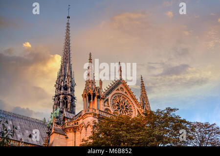 The exterior side and spires of the Notre Dame Cathedral in Paris France as the sun sets with the apostle statues climbing the spire Stock Photo