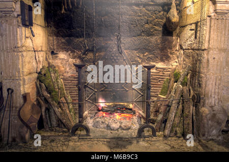 Medieval castle kitchen. Stone fireplace with antique equipment in medieval castle Stock Photo