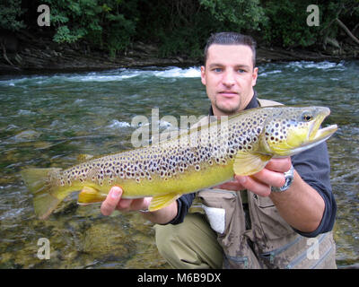 fly fishing, catch of fish, lucky fisherman holding a massive brown trout Stock Photo