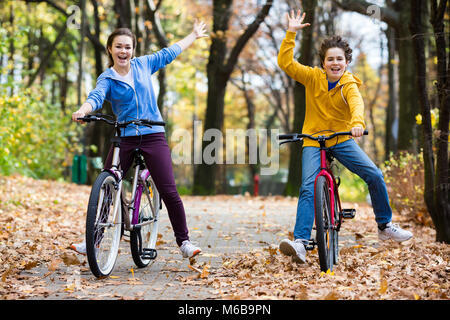 Urban biking - teens riding bikes in city park Stock Photo