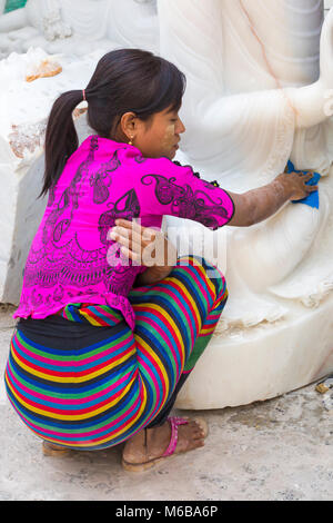 Young woman rubbing down marble Buddha, Amarapura, Mandalay, Myanmar (Burma), Asia in February - working at marble stone carving workshops in dust Stock Photo