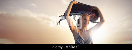 Composite image of smiling woman holding scarf in the air Stock Photo