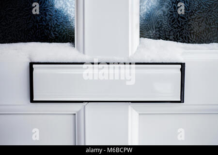 White letterbox on a white door, with snow. Stock Photo