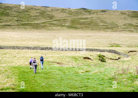 Walkers in a countryside field with a large hill ahead of them. Vale of Edale, Derbyshire, Peak District, England, UK Stock Photo
