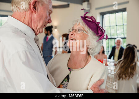 Senior couple are sharing a dance at a wedding. They are looking lovingly at each other while they dance. Stock Photo
