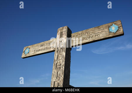 A wooden signpost on the South Downs marking the Greenwich Meridian. It points left to the 'Western Hemisphere' and right to the 'Eastern Hemisphere'. Stock Photo