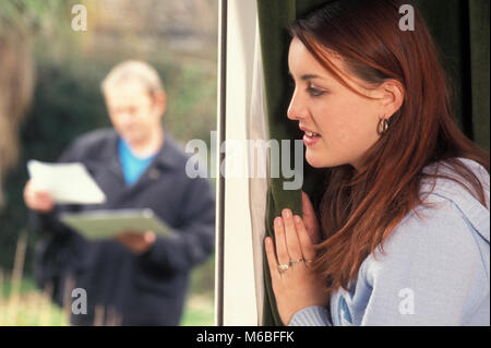 anxious teenage girl standing by window as postman delivers a letter Stock Photo