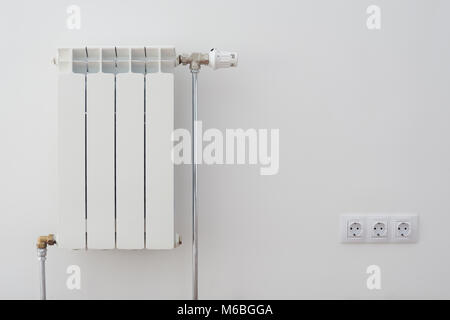 Home radiator heater on white wall. Warming equipment for apartment Stock Photo