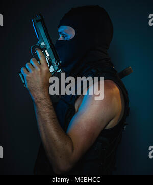 hit man, armed and dangerous man with balaclava and bulletproof vest, concept killer contract Stock Photo