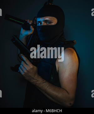 hit man, armed and dangerous man with balaclava and bulletproof vest, concept killer contract Stock Photo