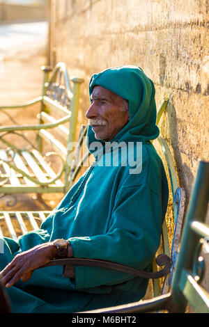 Portrait of an old man in traditional Moroccan clothing sitting on a bench, outside the walls of Fes el Bali, Fes, Morocco Stock Photo