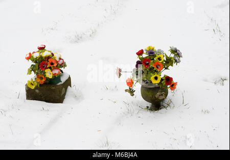 Silk flowers on graves in winter. Stock Photo