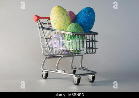 Easter eggs - colorful multicolored chocolate eggs in shopping trolley or cart for Easter gifts. Indicates cost and commercialisation of Easter celebr Stock Photo