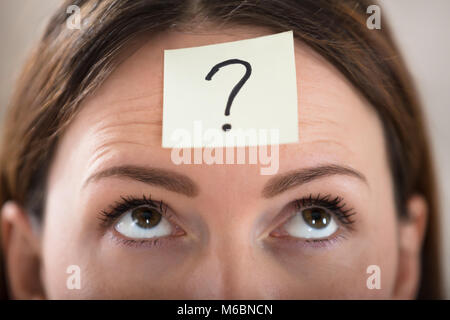 Close-up Of A Businesswoman's Forehead With Question Mark On Sticky Note Stock Photo