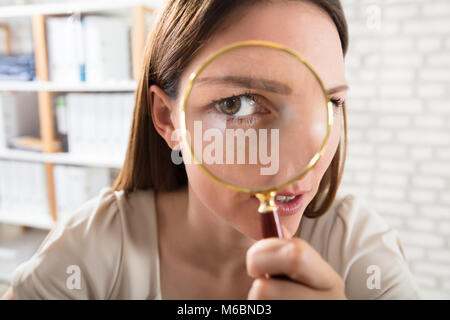 Close-up Of A Young Businesswoman Looking Through Magnifying Glass Stock Photo