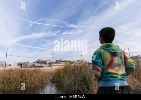 Mosul, Iraq. 8th December 2016 - A boy looks at fighter jet trails in the sky during the retaking of Mosul by the Iraqi army supported by a coalition. Stock Photo