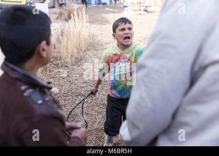 Mosul, Iraq. 8th December 2016 - A boy fights off tries to whip a man with a tyre tube to trying to steal aid during a United Nations distribution Stock Photo