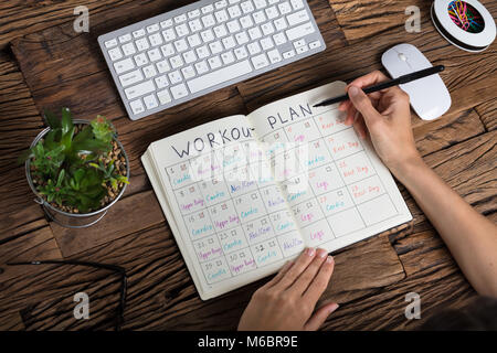 Close-up Of A Human Hand Making Workout Plan On Notebook Stock Photo