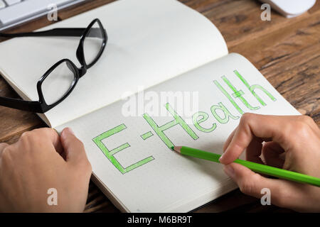 Close-up Of A Businessperson Drawing E-health Concept On Notebook Stock Photo