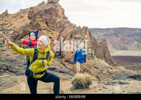 Couple hiking with baby boy travelling in backpack. Hikers family, adventure with child on autumn family trip in mountains. Vacations journey with inf Stock Photo