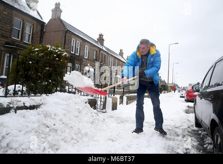 A man clears snow from outside his house in Portobello, Edinburgh, as the severe weather conditions continue. Stock Photo