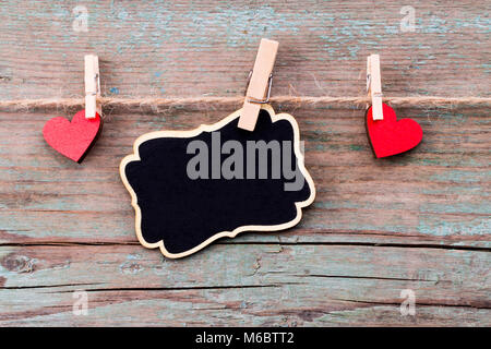 A red heart shape and a blackboard with Happy Valentine's Day text on rustic wooden table. Stock Photo