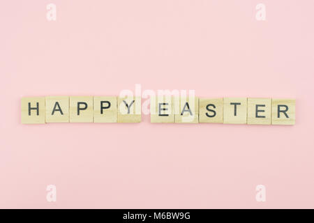 Text wooden blocks spelling the word happy easter on pink background Stock Photo