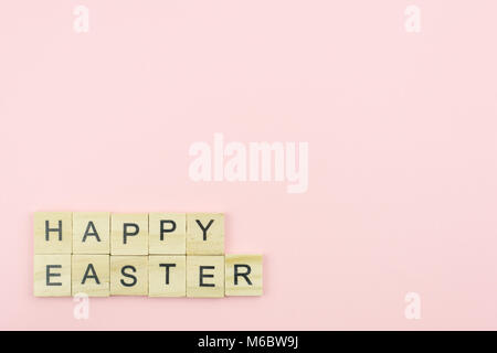 Text wooden blocks spelling the word happy easter on pink background Stock Photo