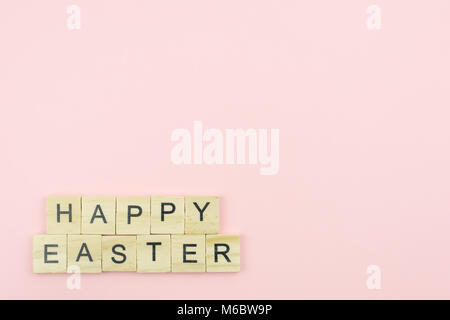 Text wooden blocks spelling the word happy easter on pink background Stock Photo