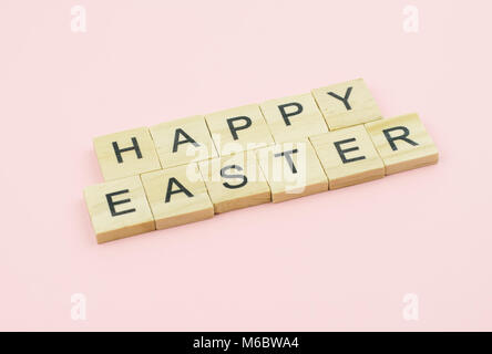 Text wooden blocks spelling the word happy easter on pink background Stock Photo