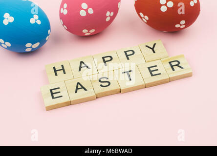Text wooden blocks spelling the word happy easter on pink background Stock Photo