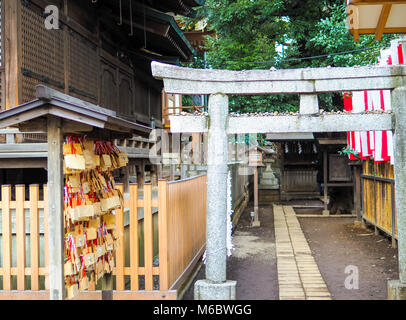 Shinto shine small inner courtyard in Tokyo,Japan. On left are prayer plaques called Ema. Entrance gate and smaller shrine in centre.All text removed. Stock Photo
