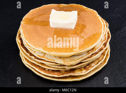 Stack of pancakes in syrup on dark background. Stock Photo