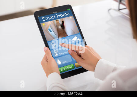 Close-up Of A Person's Hand Using Smart Home System On Digital Tablet Stock Photo