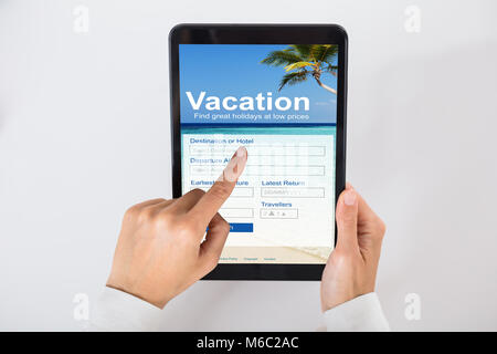 High Angle View Of A Businessperson's Hand Filling Online Vacation Form On Digital Tablet Stock Photo