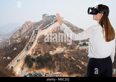 Woman Using Virtual Reality Device Against Great Wall Of China Stock Photo