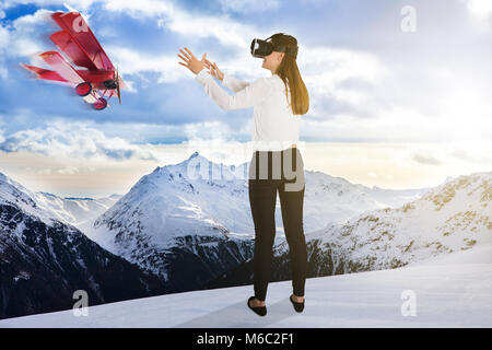 Airplane Flying Near Young Woman Wearing Virtual Reality Glasses In Snowy Weather Stock Photo