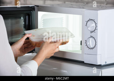 Close-up Of A Person Removing Prepared Food From Microwave Oven Stock Photo