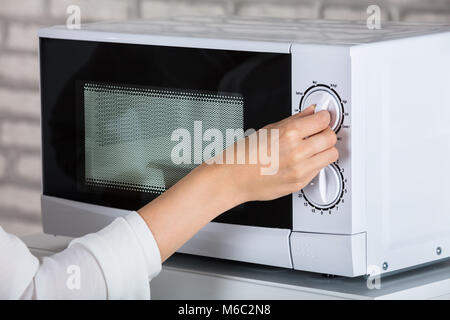 Woman Using Microwave Oven For Heating Food At Home Stock Photo