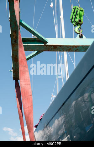 Sailing boat lifted by a crane in the port Stock Photo