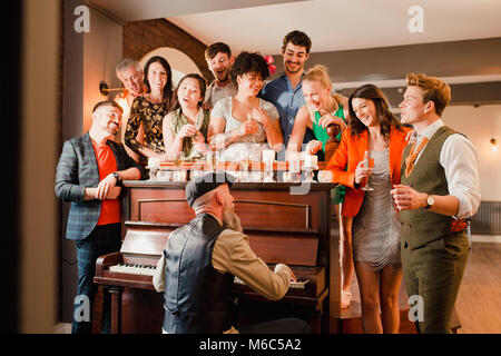 Wedding guests are singing along with the pianist as he plays. Stock Photo