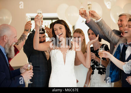 Bride is dancing and raising her glass with all of her guests on her wedding day. Stock Photo