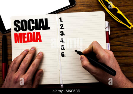 Word, writing Social Media. Business concept for Global Internet Network Written book, wooden background with businessman hand, finger writing on the  Stock Photo