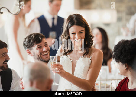 Happy bride and groom are socialising with the guests at their wedding reception. Stock Photo