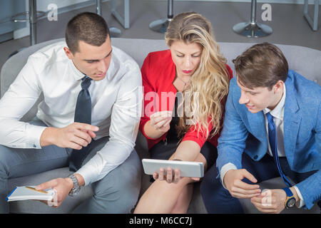Small business team discussing and brainstorming future steps and ideas, working and looking at digital tablet device Stock Photo